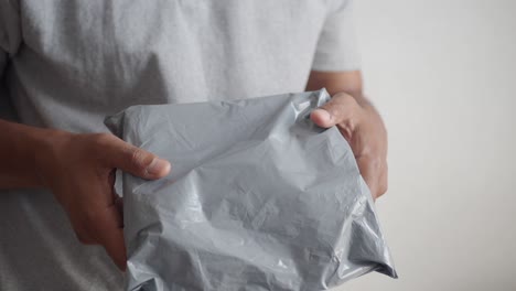 person holding a gray plastic package