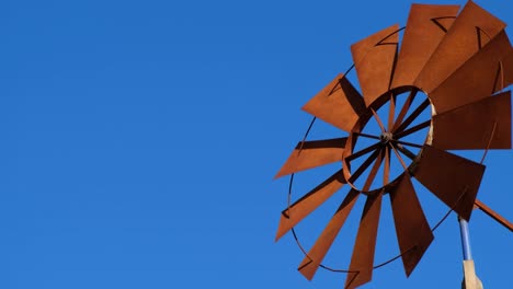 the wind pump fan blades are moving fast against the blue sky.