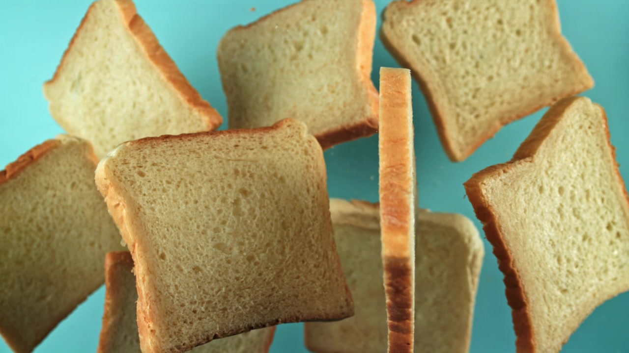 Slices of White Bread Falling in Slow Motion Against a Blue Background