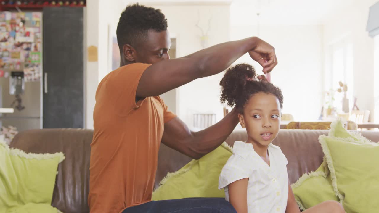 padre afroamericano atando el cabello de su hija