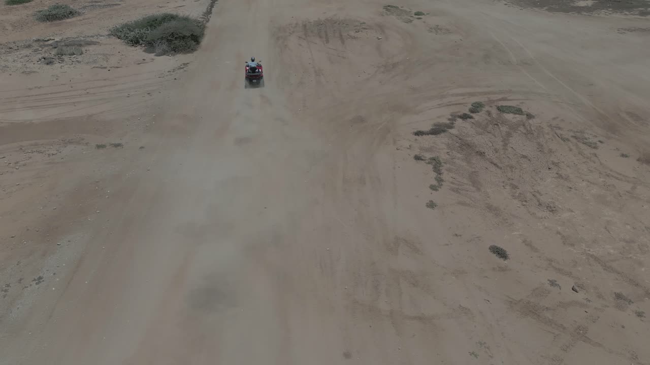AEREA: Ripresa con drone di una persona a bordo di un quad sulla sabbia.