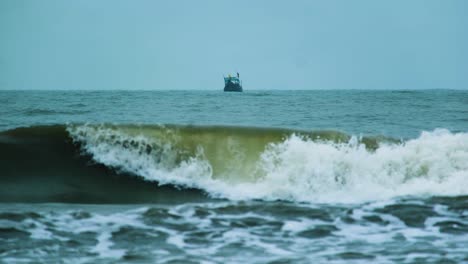 industrial fishing boats sailing in distance over ocean with rough waves