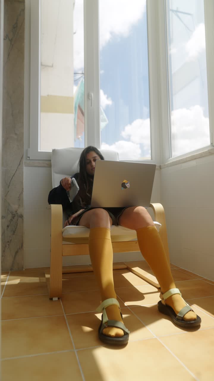 발코니에서 노트북을 쓰고 있는 여자