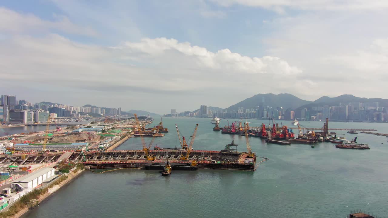 Converting an old runway strip into a Housing and business district at Kai Tak downtown Hong Kong, with vast infrastructure development land and an underwater tunnel laying operation, Aerial view.