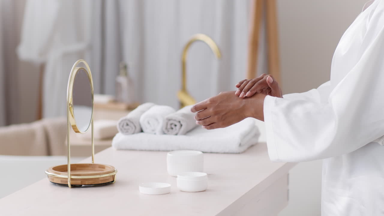 Woman applying hand cream in a spa-like bathroom