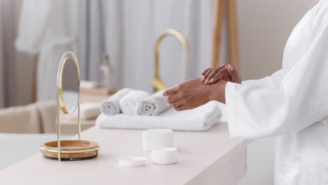 woman applying hand cream in a spa-like bathroom
