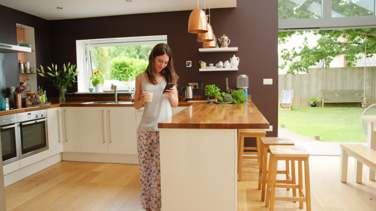 Donna che usa lo smartphone in una cucina accogliente