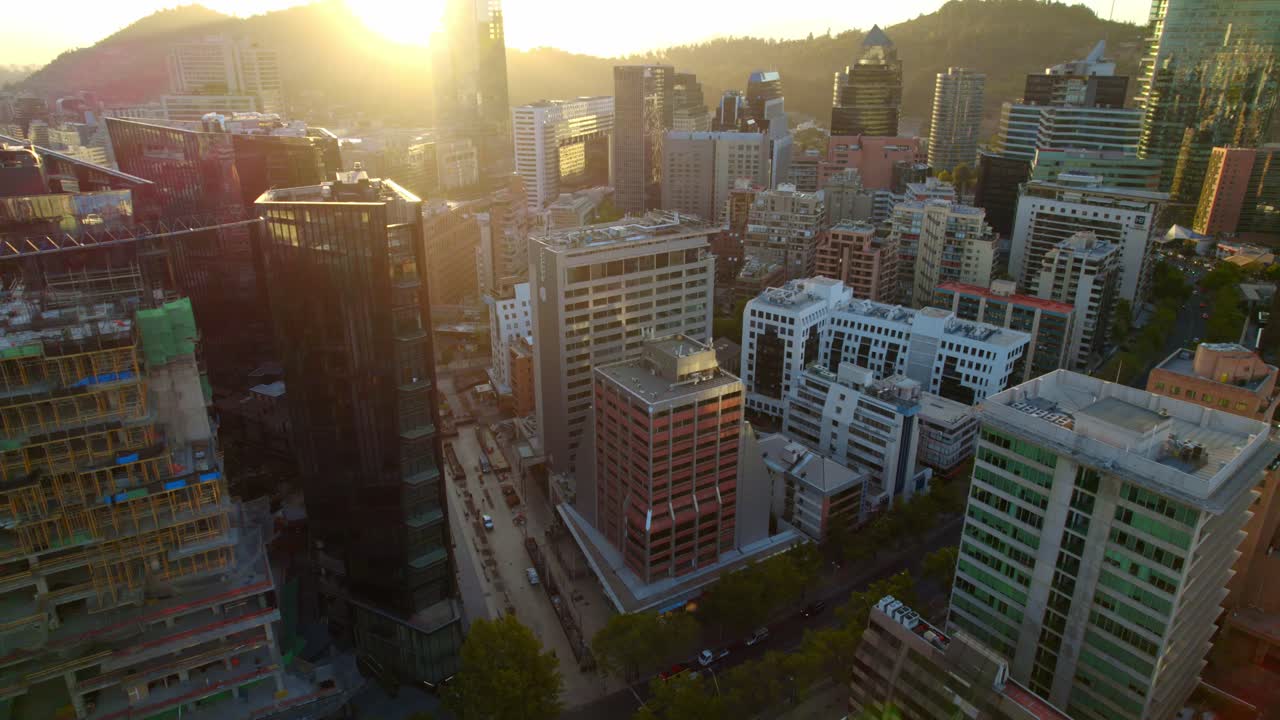 Aerial tilt shot of sunset behind vibrant buildings in Las Condes, Santiago de Chile