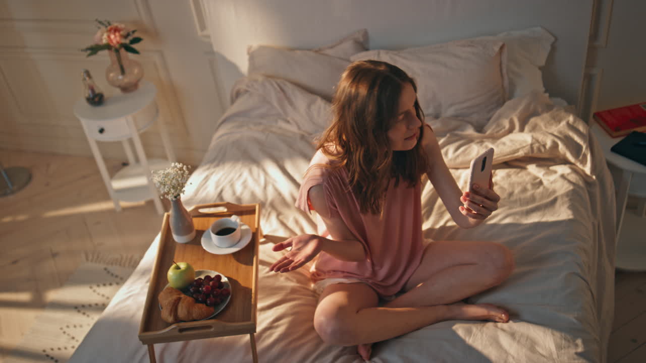 블로거 소녀가 집에서 드폰으로 동영상을 녹화합니다. 웃는 십대가 얘기합니다.