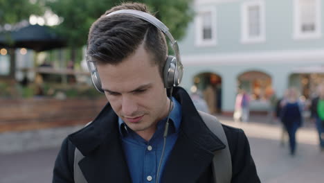 close up portrait of attractive young caucasian man wearing headphones listening to music using smarphone app enjoying relaxed urban travel