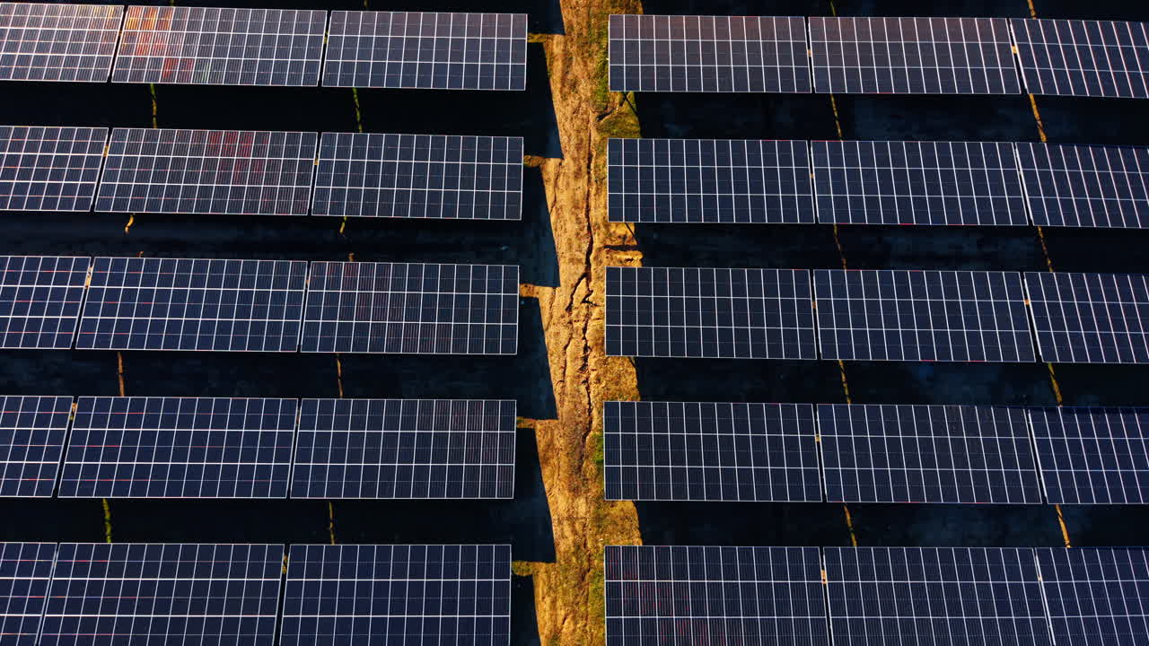 Ripresa aerea verticale di moduli fotovoltaici e sentiero di accesso. Vista ravvicinata dall'alto di file di pannelli solari separate da un percorso a terra.