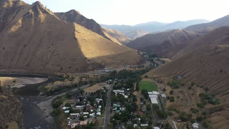 aerial drone shot of salmon river and town of riggins idaho through high mountains.