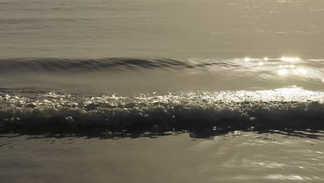 Océano-Plateado-Al-Amanecer,-Suaves-Olas-Que-Reflejan-La-Luz-Del-Sol,-Cámara-Lenta-Abstracta