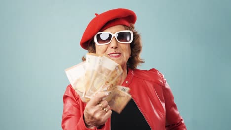 happy elderly woman in red beret and sunglasses with money