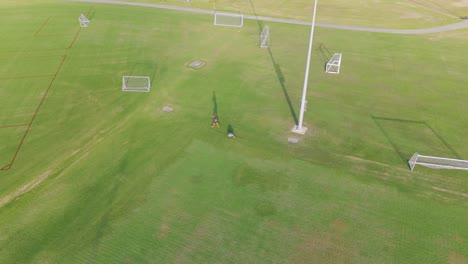 Aerial drone footage captures a soccer field with players moving across the grass under bright daylight
