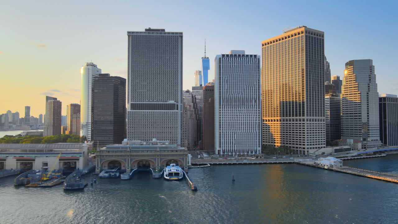 Golden Hour Sun on Skyscrapers. Spiral Aerial Shoot of Downtown Manhattan, from East River to Battery Park, framing One World Trade Center at the end.