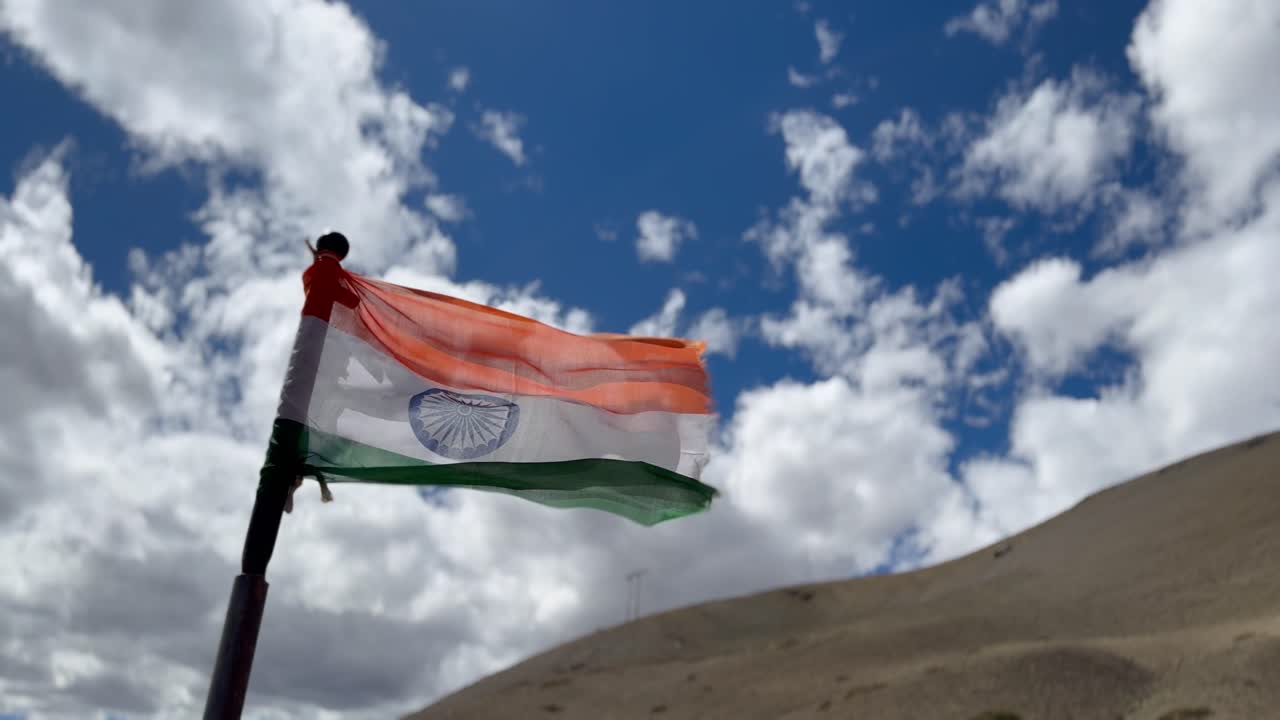 Indian flag waving proudly against a backdrop of a bright blue sky with fluffy white clouds