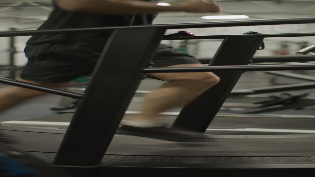 Young Man Running on Treadmill during Cardio Workout in Gym