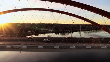 aerial-shot-crossing-Mississippi-River-at-dusk,-with-the-evening-sun-causing-a-dramatic-starburst-lens-flare-effect-in-the-drone-camera-lens