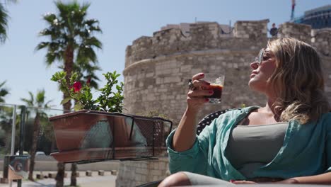 young confident blonde woman drinks a coffee in mediterranean european cafe