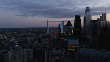 Evening-elevated-footage-of-tall-modern-skyscrapers-against-twilight-sky.-Office-buildings-in-business-hub.-London,-UK