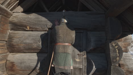 medieval warrior in front of a log cabin