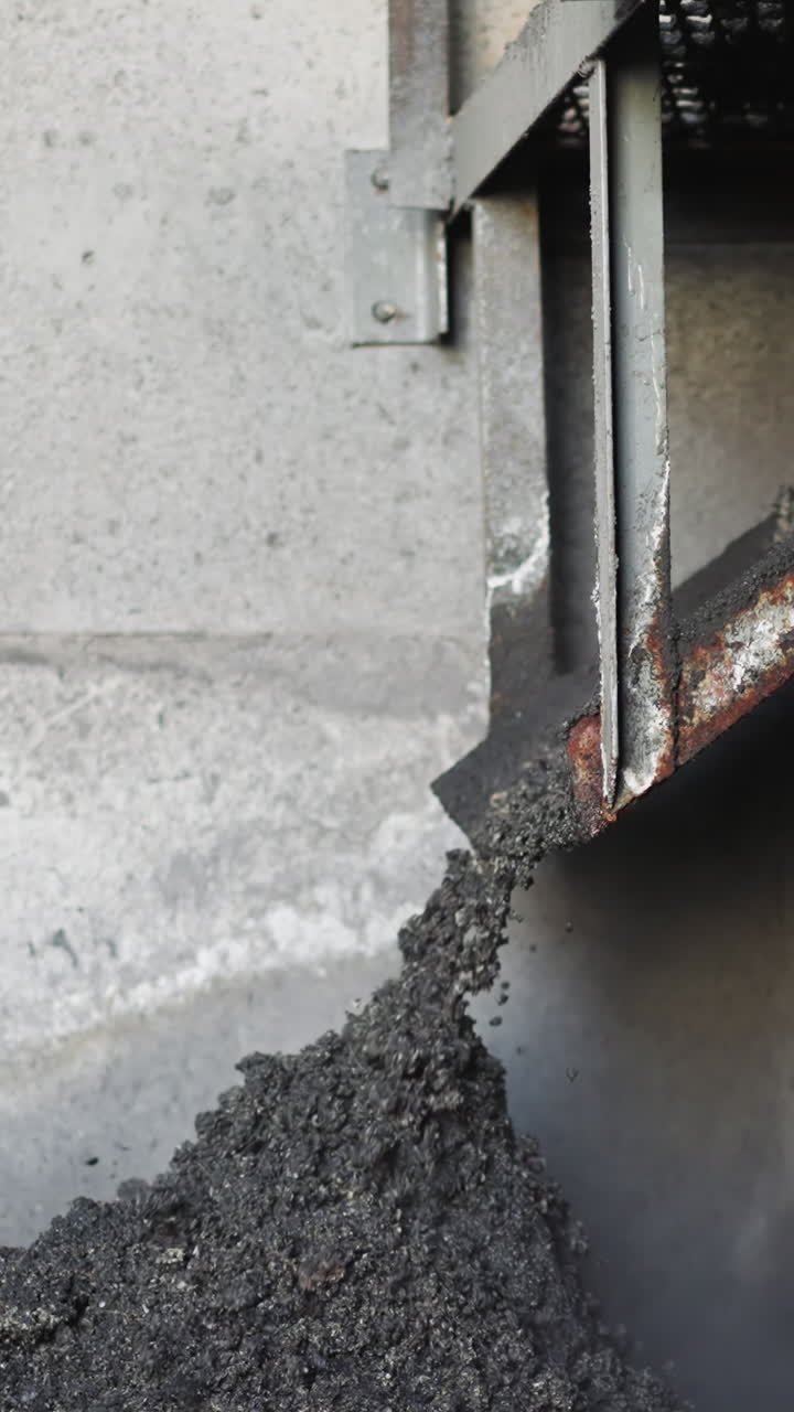 Pouring coal slag from metal feeder in industrial storage slow motion. Waste fossil fuel collected in heating station warehouse. Burnt charcoal pile