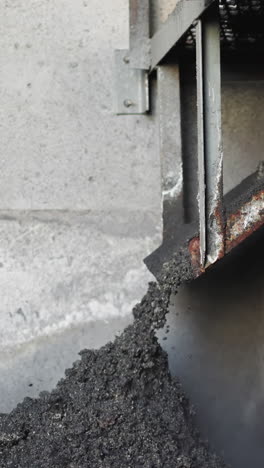 pouring coal slag from metal feeder in industrial storage slow motion. waste fossil fuel collected in heating station warehouse. burnt charcoal pile