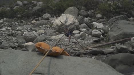 a trainer of a mountaineering institute of the himalayas crossing the mountainous river by rope, practicing to cross the river with rope