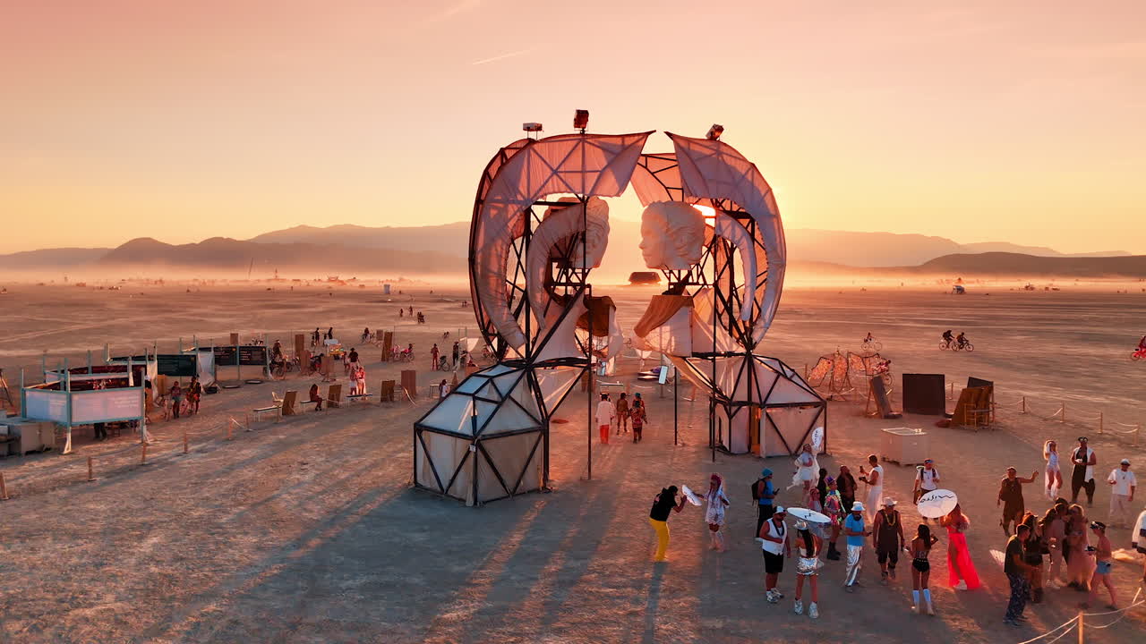 Nevada, USA, 14 August 2025: Burning Man art installation with crowd during sunset in Nevada desert.. Festival participants gather around an art sculpture as the sun sets