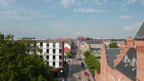 Dolly-in-aerial-view-of-one-of-the-longest-pedestrian-road-in-Denmark,-Torvegade-in-Esbjerg.-Flight-over-the-street-with-pedestrian-strolling-enjoying-good-weather-downtown