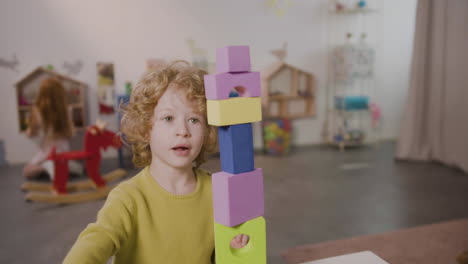 blond little boy playing with foam building blocks in a montessori school 2