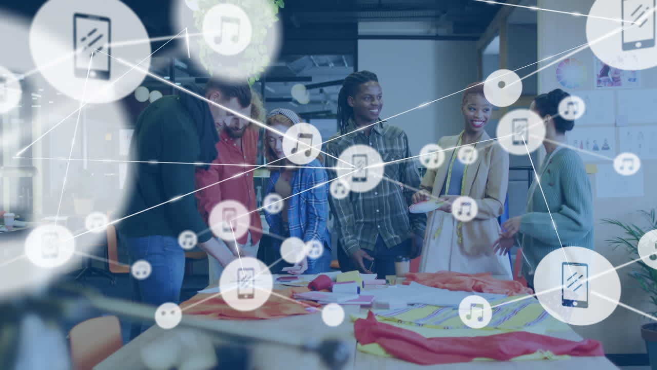 animación de música conectada e íconos de teléfono sobre compañeros de trabajo multirraciales examinando la tela en el estudio
