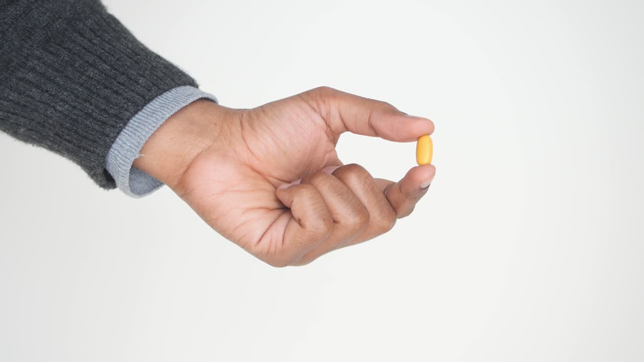 mano con una píldora amarilla