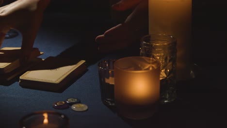 primer plano de una mujer dando lectura de cartas de tarot a un hombre en una mesa a la luz de las velas