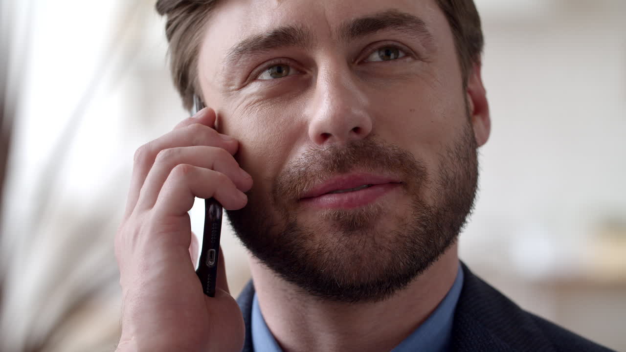 Smiling business man speaking phone emotionally at home. Guy calling cellphone.