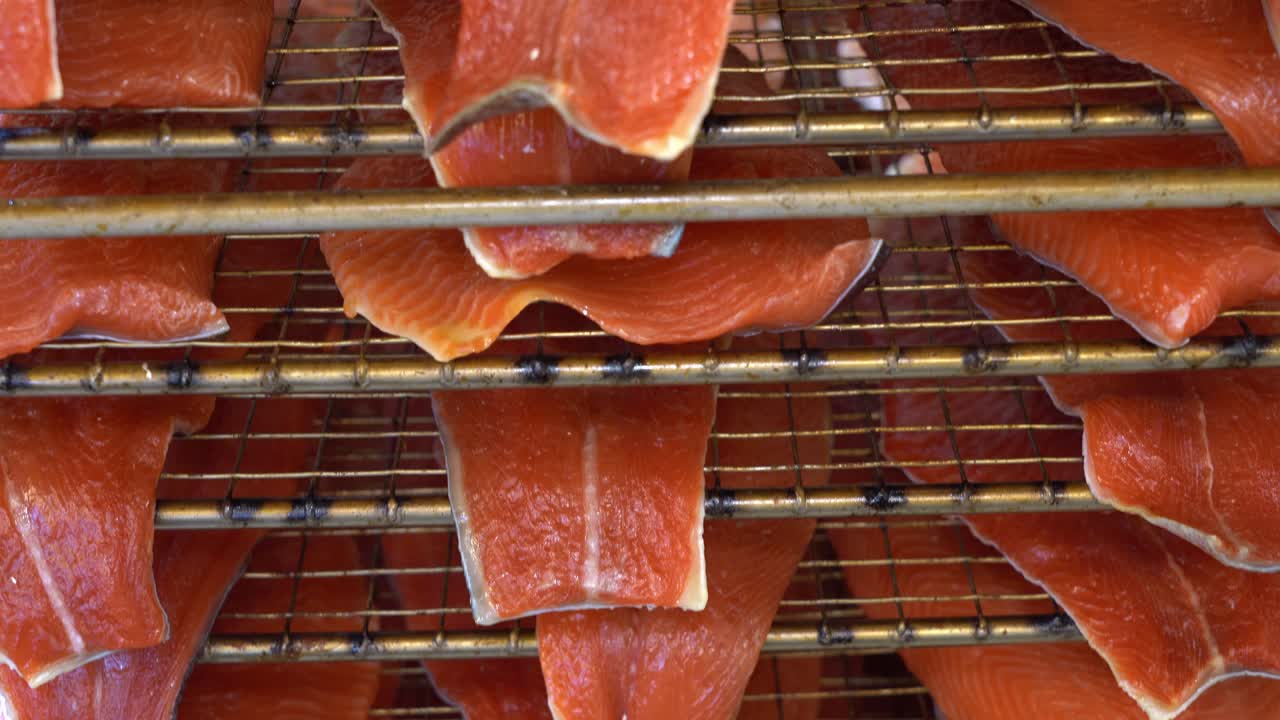 filetes de salmón en capas uno al lado del otro en una pantalla de rejilla que viene directamente del ahumador - primer plano