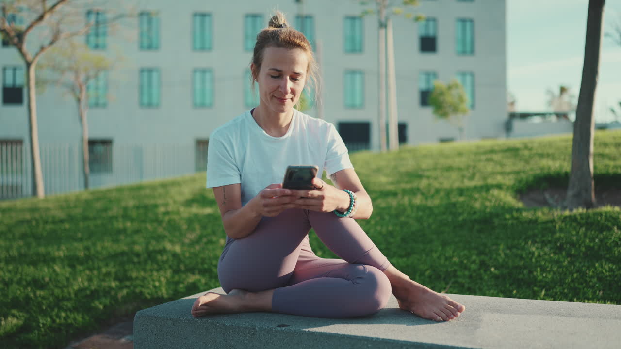 una joven deportiva usando el teléfono en el parque de la ciudad.