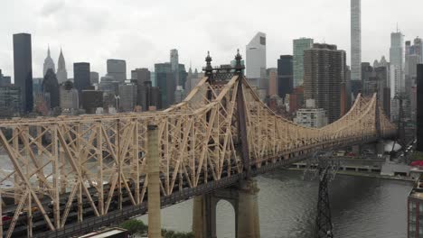 full drone aerial pan of the queensboro bridge from manhattan, nyc to queens in the daytime with a bus leaving manhattan, poetic view of someone leaving the big city