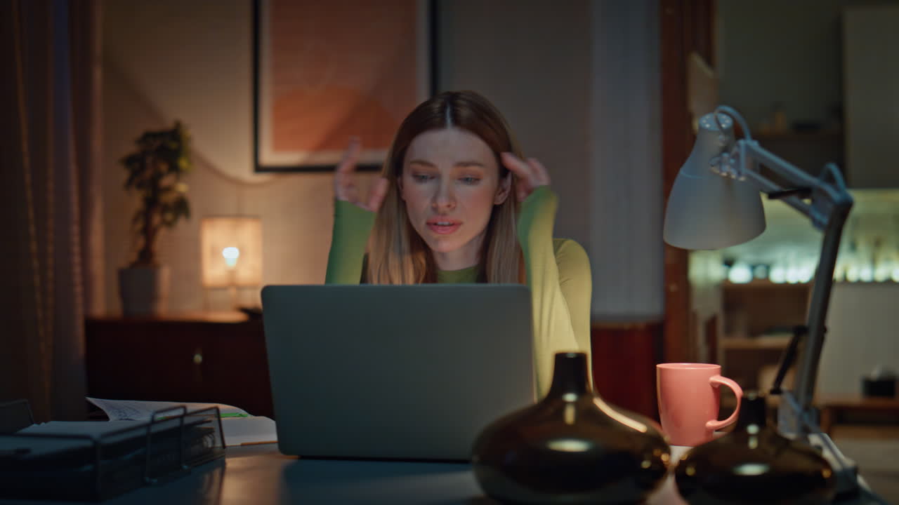 Disappointed freelancer video calling by laptop in dark home workplace close up.