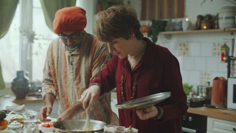 indian food blogger teaching young woman to cook traditional dish in kitchen