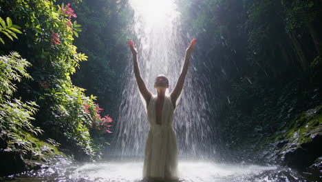 Woman in a White Dress by a Waterfall in a Tropical Forest