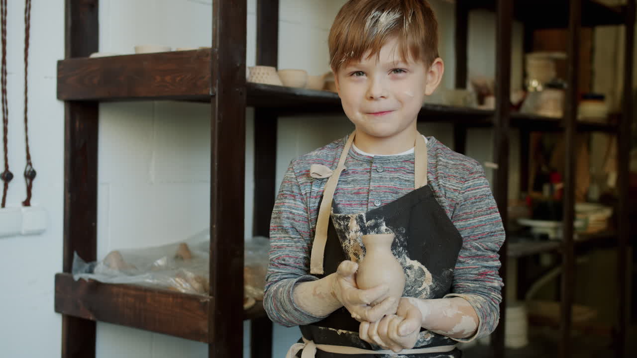 Boy holding a clay pot in pottery studio