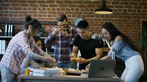 colleagues in office eating pizza together