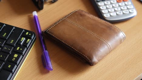 brown leather wallet on a desk with accessories