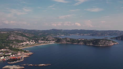 Drone-shot-of-a-beach-and-cabins-in-Spangereid,-Lindesnes,-South-of-Norway-on-a-beautifull-summer-day