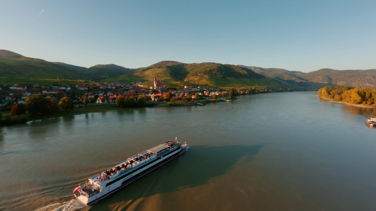 Ascending fpv shot of a danube boat passing weissenkirchen town in the wachau valley
