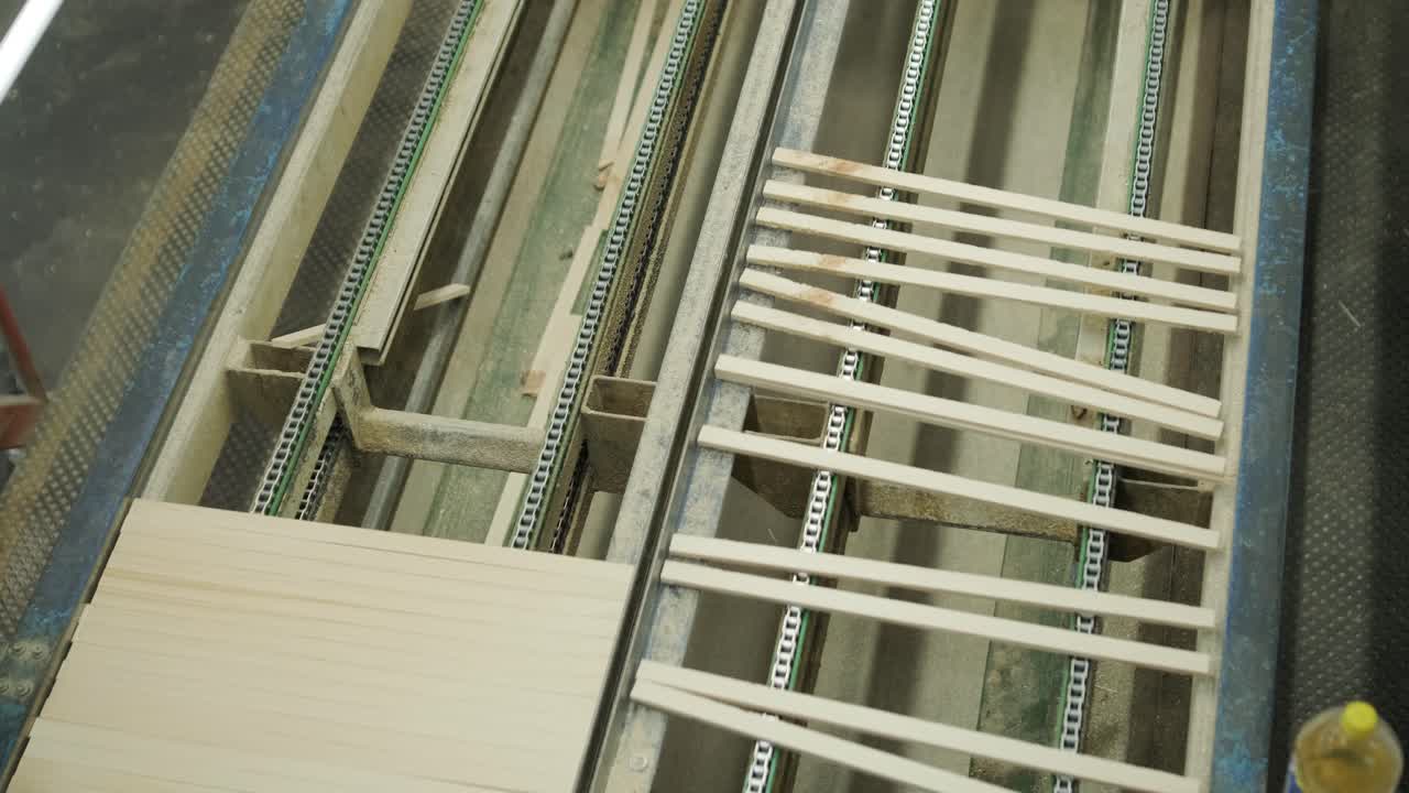 Listelli di legno che si muovono su un nastro trasportatore in una fabbrica.