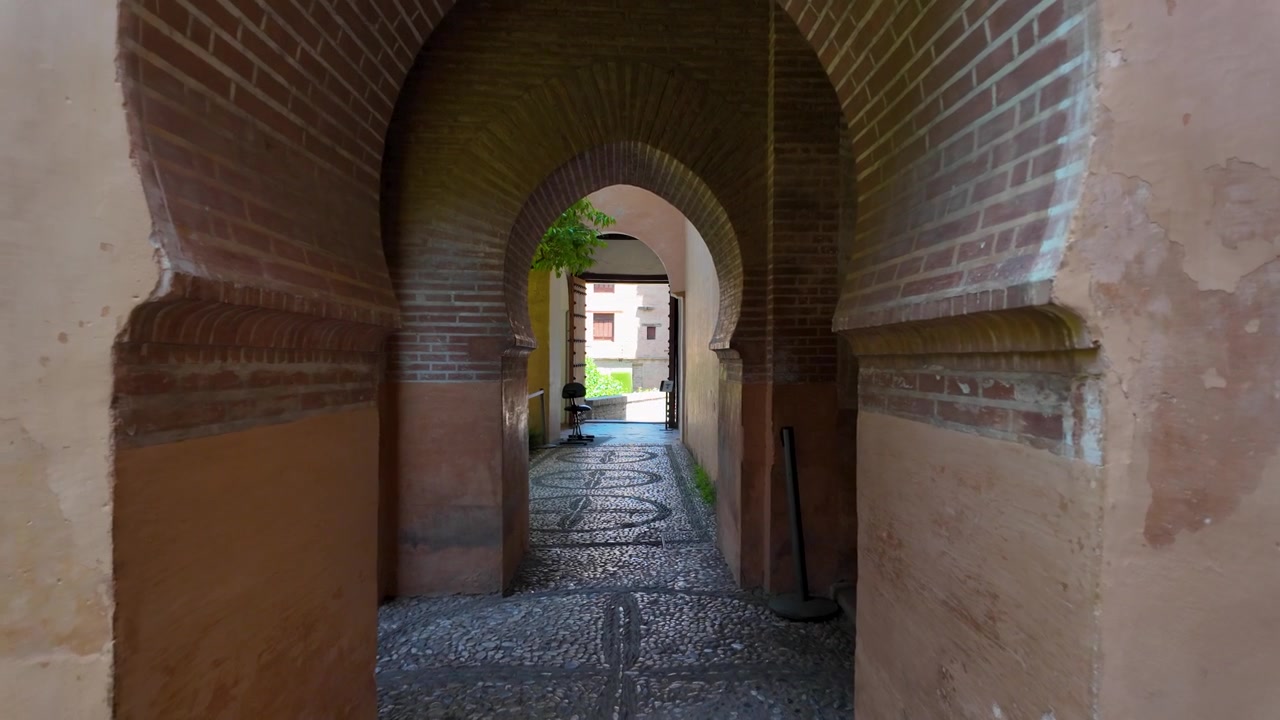 Movimento in avanti al rallentatore attraverso una serie di archi moreschi all'interno del complesso dell'Alhambra a Granada, Spagna