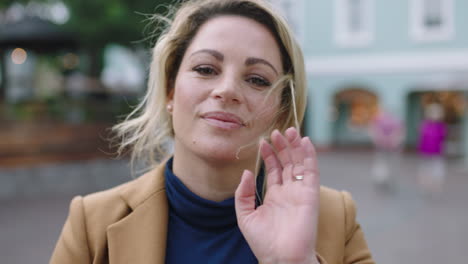 slow motion portrait of stylish blonde business woman in suit smiling at camera running hand through hair